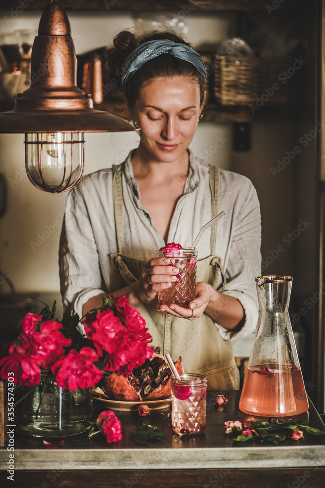 Summer refreshing cold beverage drink. Young woman in linen apron holding rose lemonade with ice in 