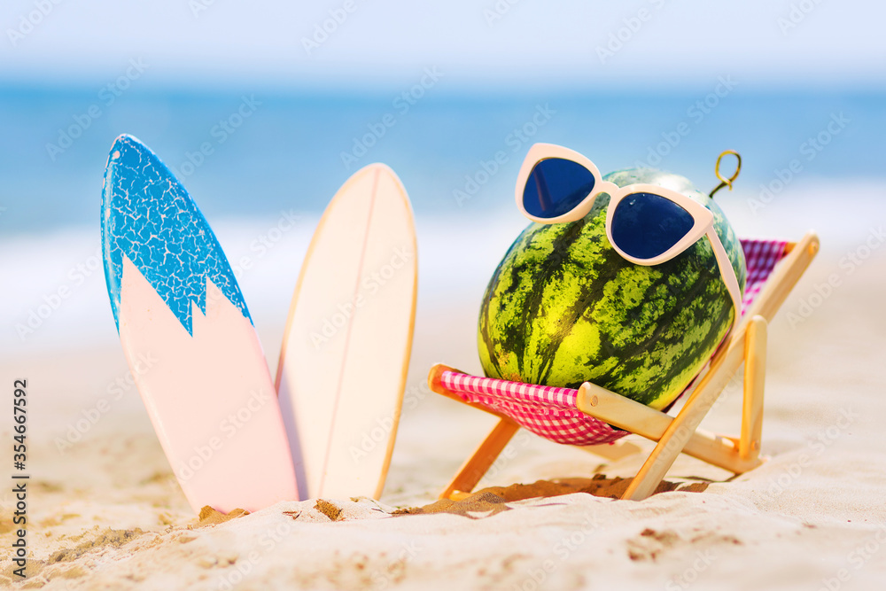 夏日生活方式图片，迷人的西瓜冲浪者躺在沙滩上的日光浴床上，背靠绿松石