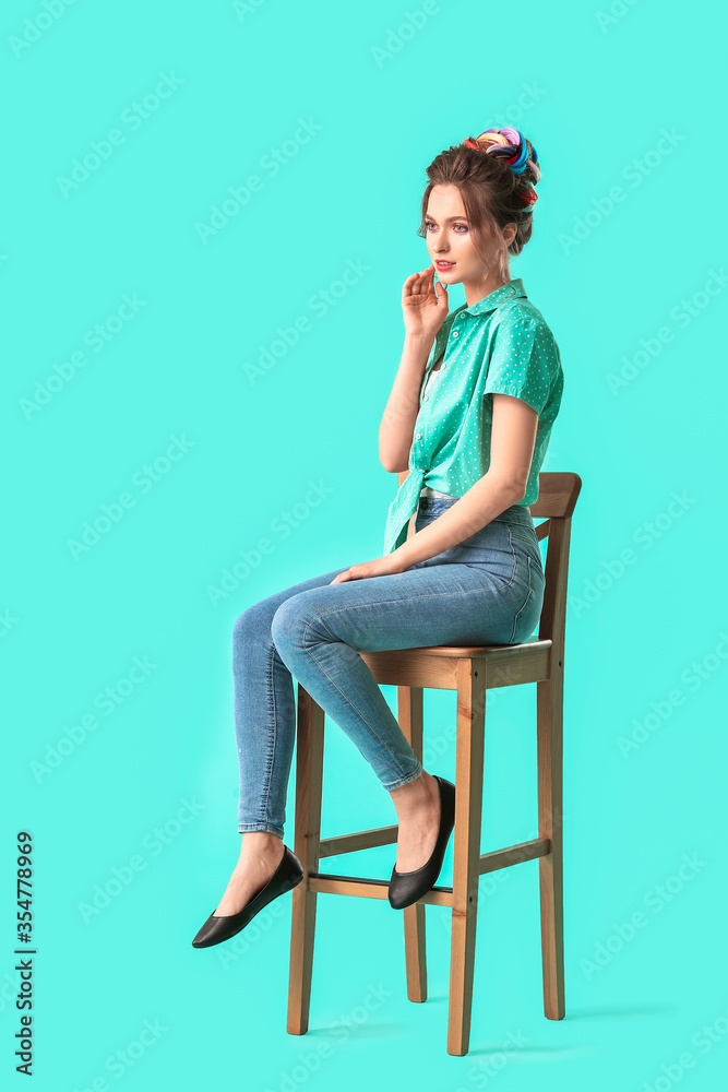 美丽的年轻女子，头发不同寻常，坐在彩色背景下的椅子上