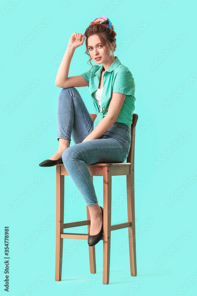 美丽的年轻女子，头发不同寻常，坐在彩色背景下的椅子上