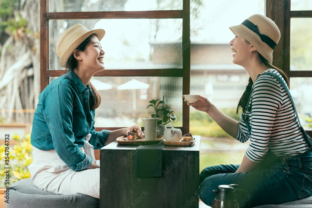 两个亚洲女孩朋友在京都当地餐厅的室内聊天时大笑的侧视图。快乐的siste