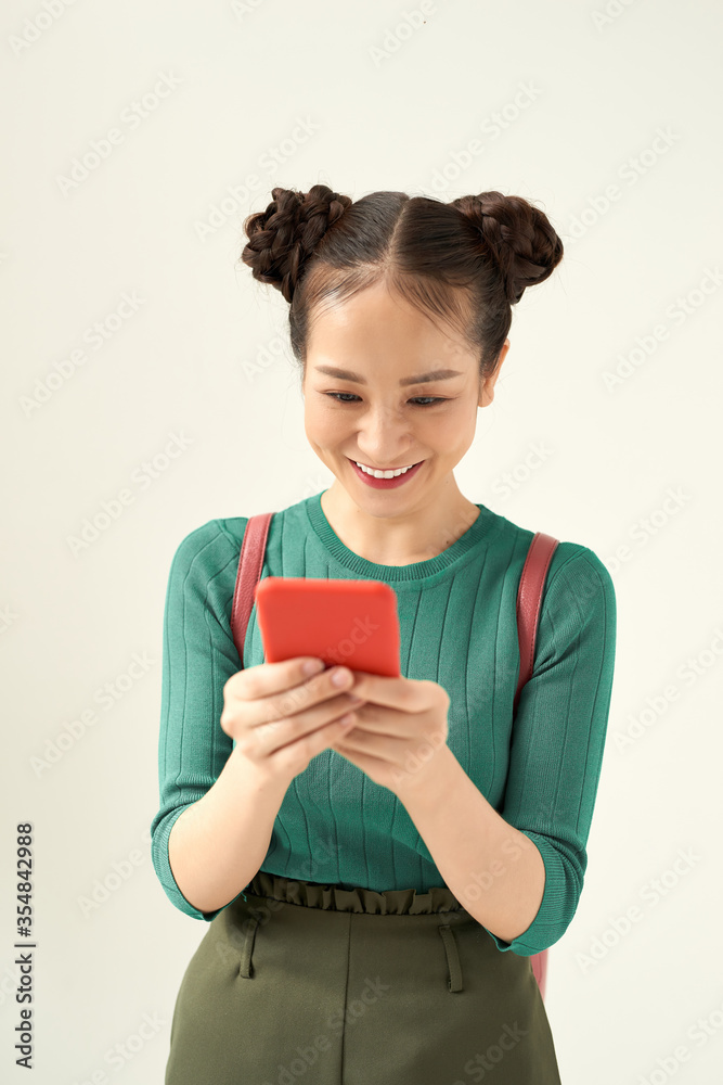 Photo of happy charming girl in eyeglasses using cellphone isolated over color background