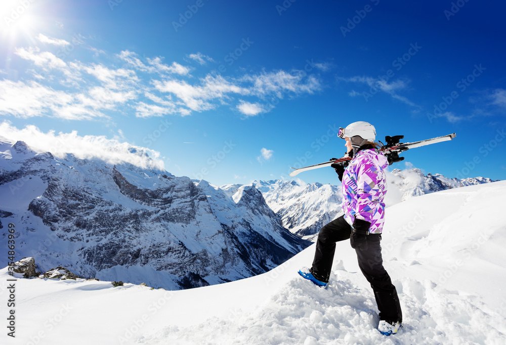 一个女孩在山顶上的侧视图，一名运动员站在肩上滑雪
