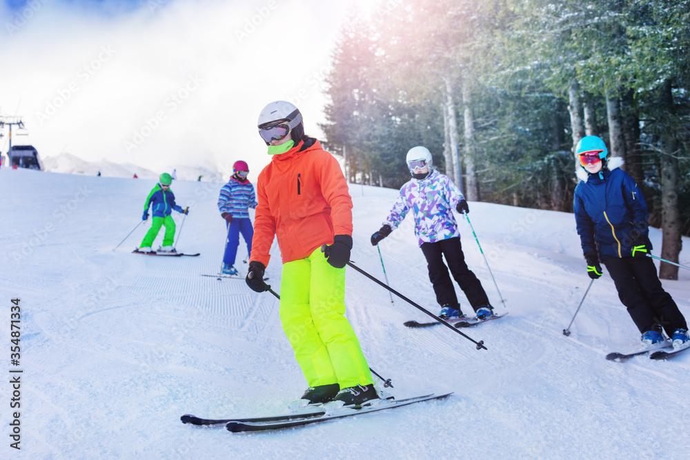 一群孩子和朋友在阿尔卑斯山度假胜地的山上滑雪，背景是森林