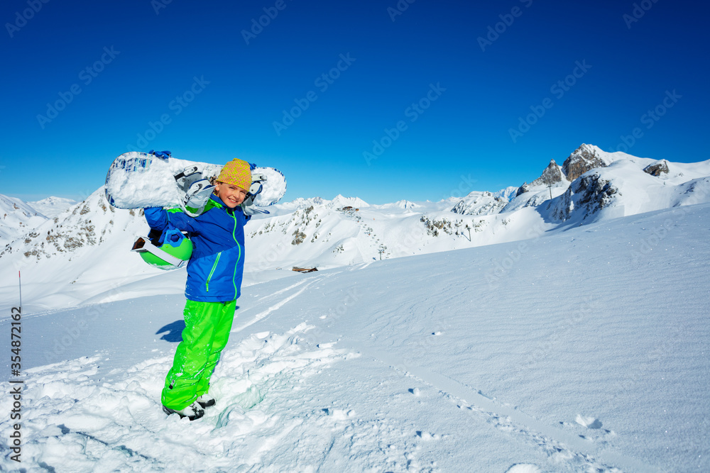 一个男孩的肖像，肩上扛着滑雪板和休闲帽，俯瞰着良好的w山全景