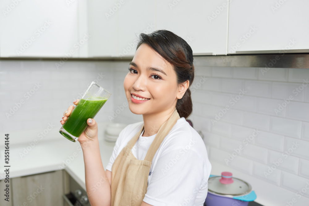排毒概念。亚洲女孩拿着自制绿色果汁的杯子，看起来很疲惫的特写肖像