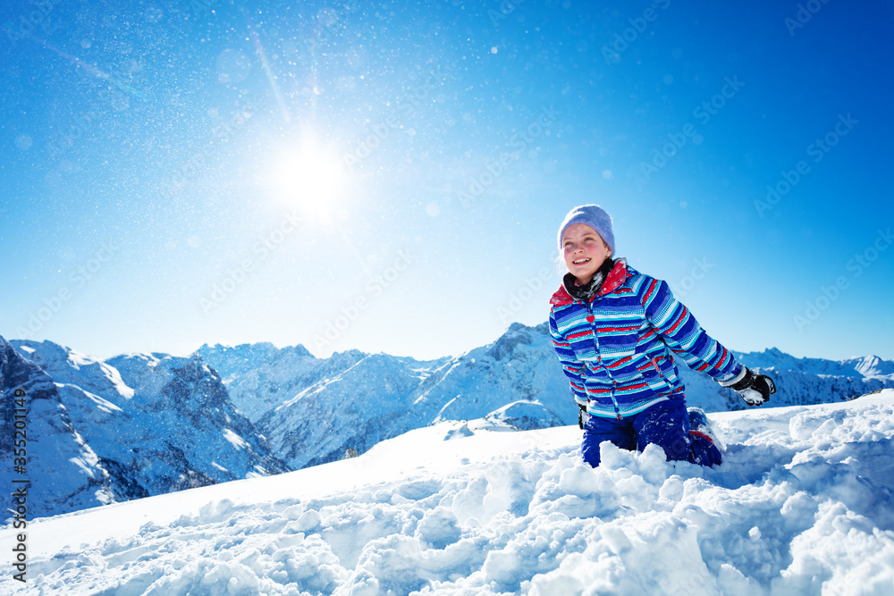 可爱美丽、面带微笑的女孩即将把雪抛向空中，在蓝天上特写