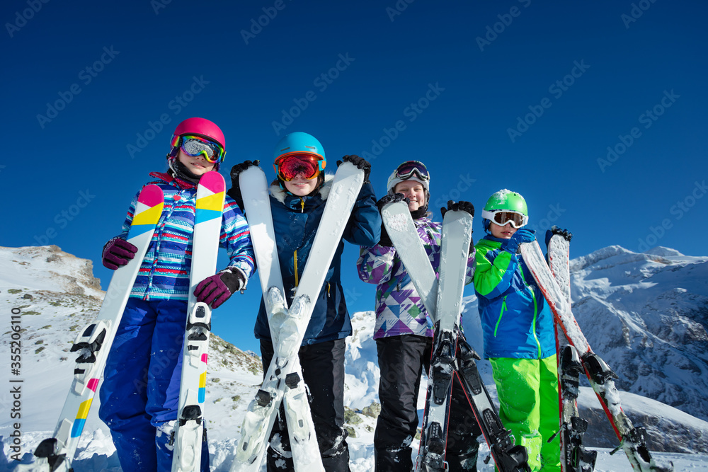 滑雪度假画像许多孩子站在那里，手里拿着运动器材，穿着彩色衣服靠在相机前