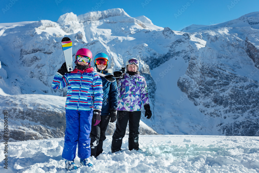 肩上扛着滑雪运动装备的女孩和一群朋友站在背地的山峰上