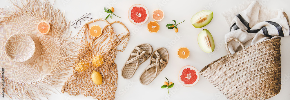 夏季心情布局。夏季天然凉鞋、草帽、沙滩拉菲亚和网袋的平躺，条纹