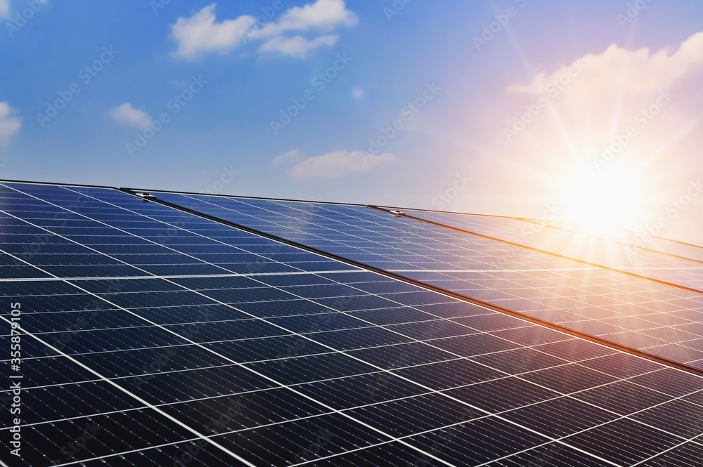 日落和蓝天背景的太阳能电池板。清洁能源概念。