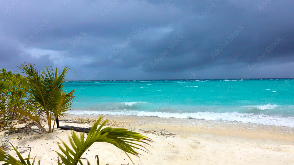 Raging tropical storm approaches the idyllic white sand beach on Himmafushi.