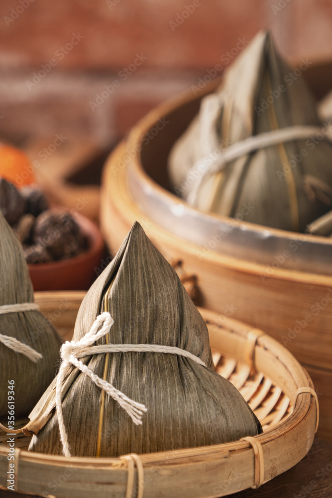 粽子——红砖木桌上的蒸笼里的中国粽子，窗户背景
