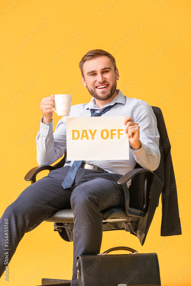 年轻的商人拿着咖啡，手里拿着彩色背景下写着DAY OFF的纸