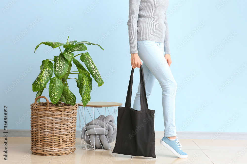 Young woman with eco bag against color wall