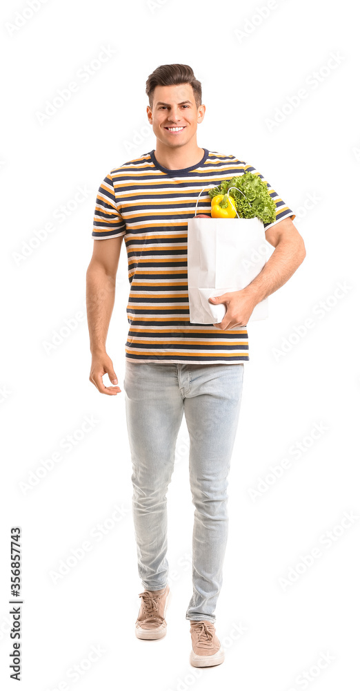 Young man holding bag with food on white background