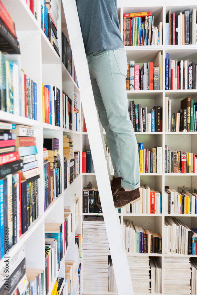 站在梯子上够图书馆里的书的人