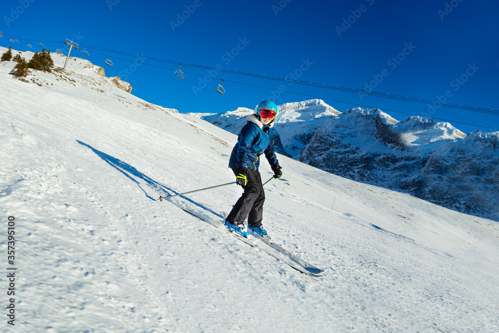 一个十几岁的女孩在滑雪坡上向下移动，看着升降椅上的相机，蓝天o