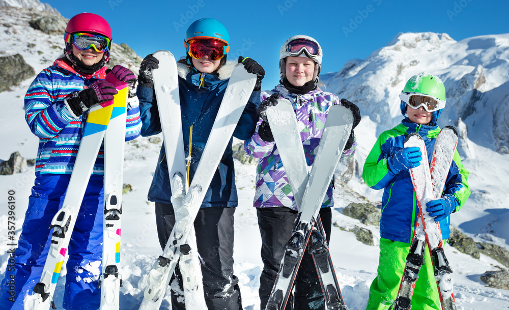 寒假概念-一群快乐的孩子站在他们面前，抱着滑雪板，靠着身子微笑