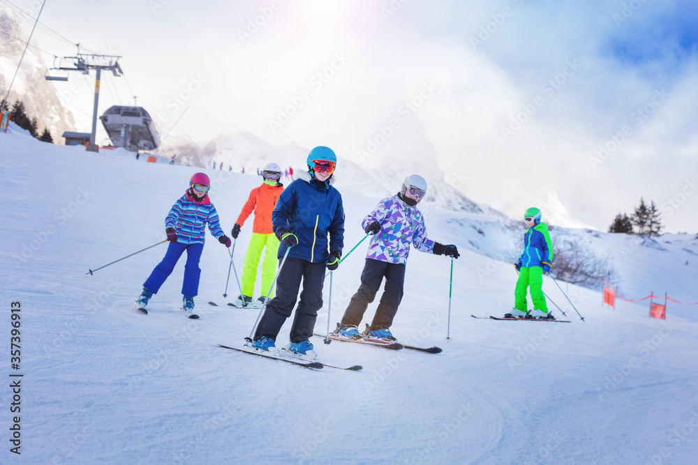 一群孩子穿着五颜六色的衣服在阿尔卑斯山的山坡上一起滑雪
