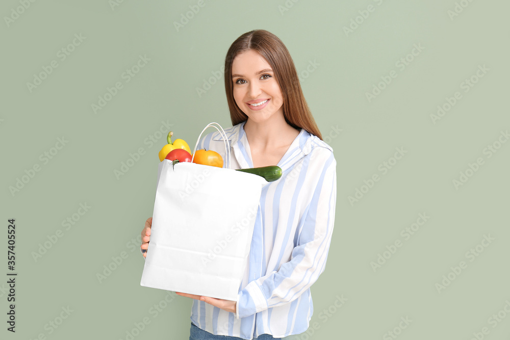 年轻女子拿着彩色背景食物的袋子
