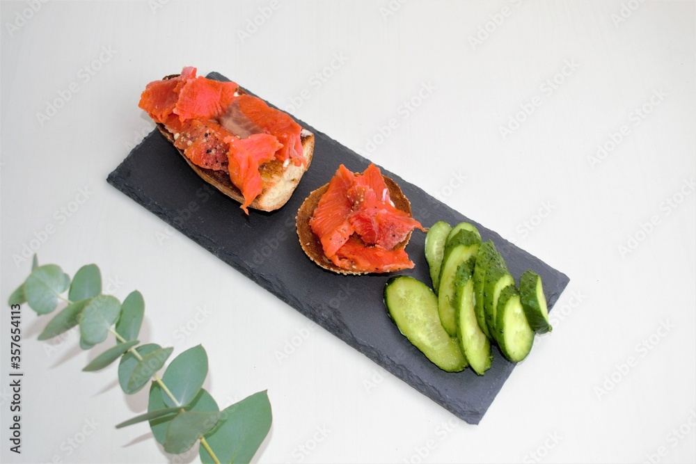 Food composition on a light background. A slate board on which mini bagels and bruschettas with curd