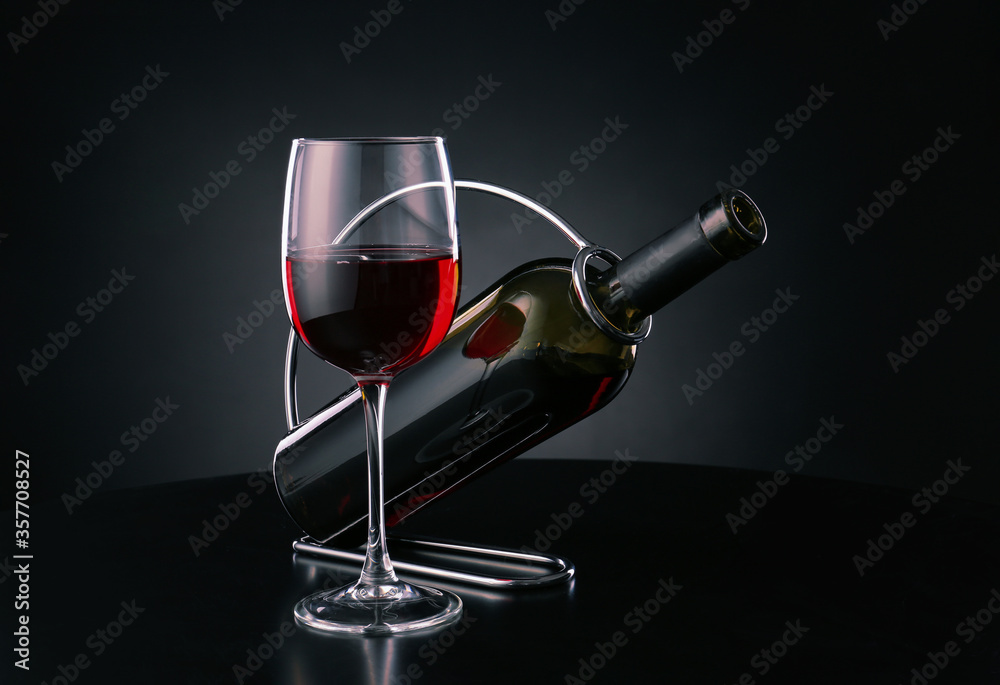 深色背景上有一瓶和一杯葡萄酒的支架