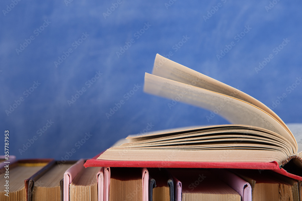 Education and reading concept - group of books on the wooden table, blue blackboard background. Teac
