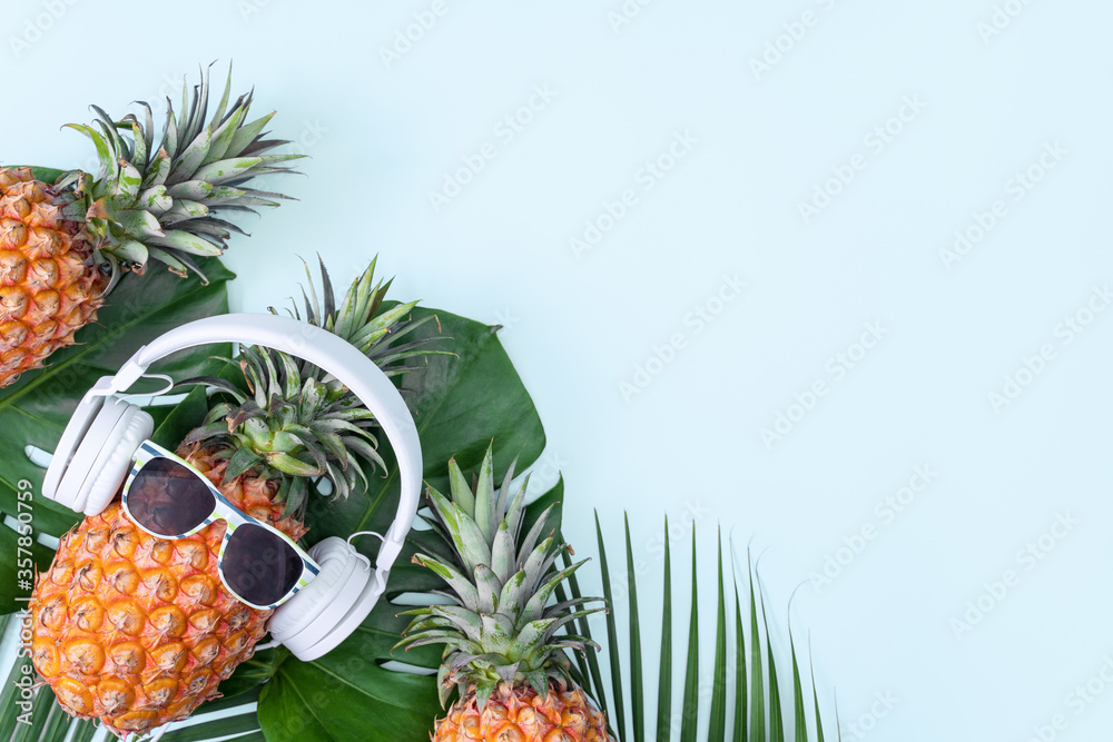 Funny pineapple wearing white headphone, concept of listening music, isolated on colored background 