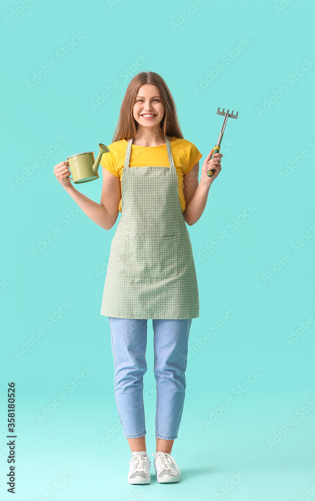 一个年轻的女人，在彩色背景上拿着喷壶和耙子