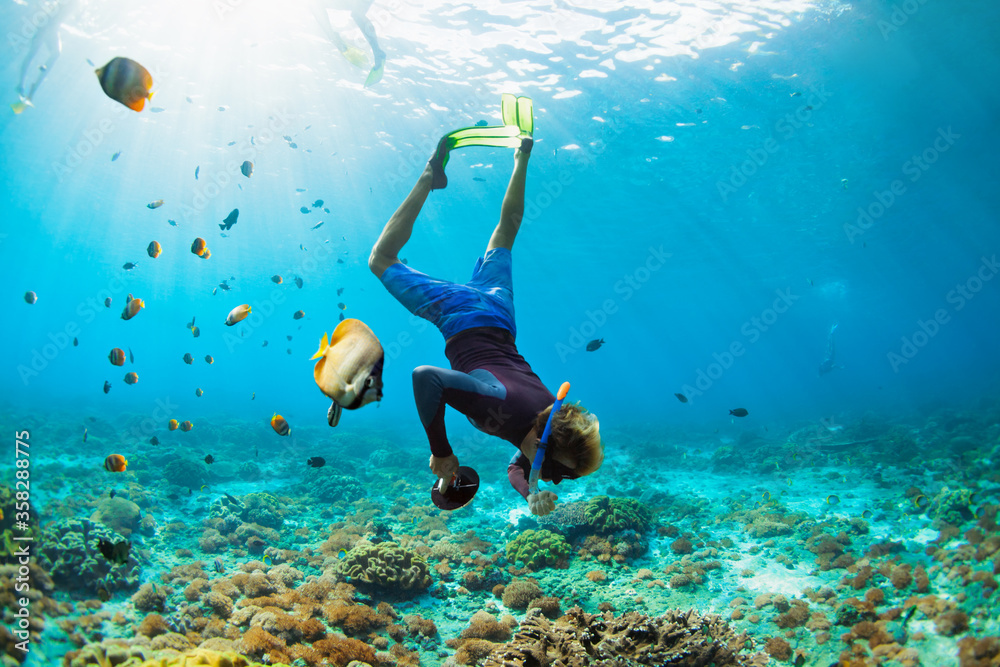 家庭度假快乐。戴着浮潜面具的男子带着相机与热带鱼一起潜入水下