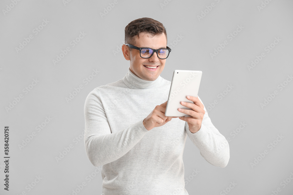 灰色背景下带平板电脑的年轻商人