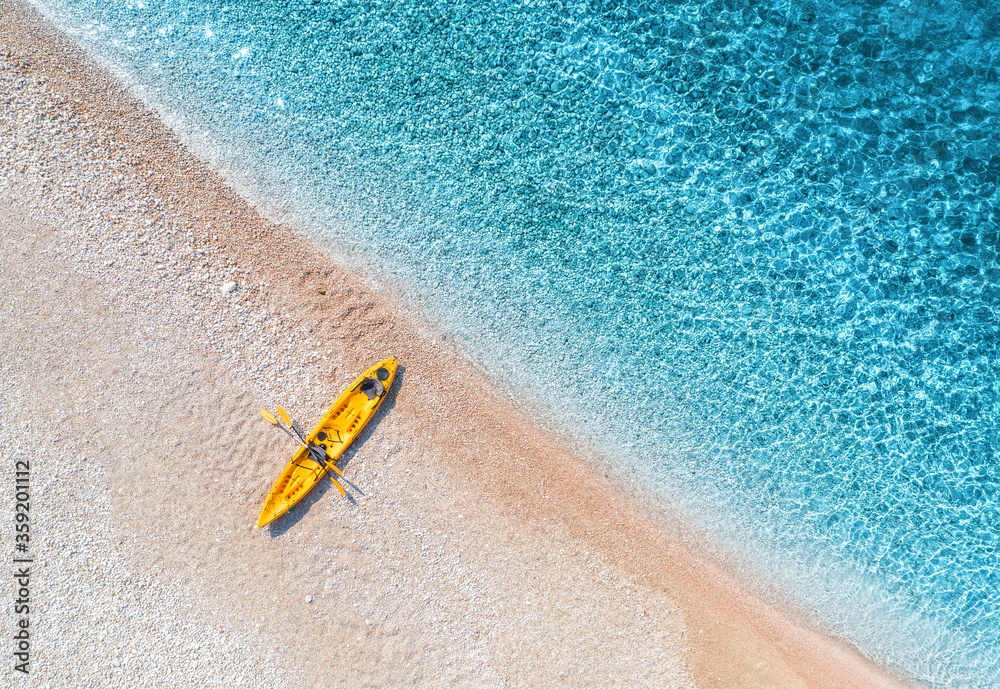 空中俯瞰空旷的沙滩，黄色的独木舟，阳光明媚的b海岸，透明的蓝色海水