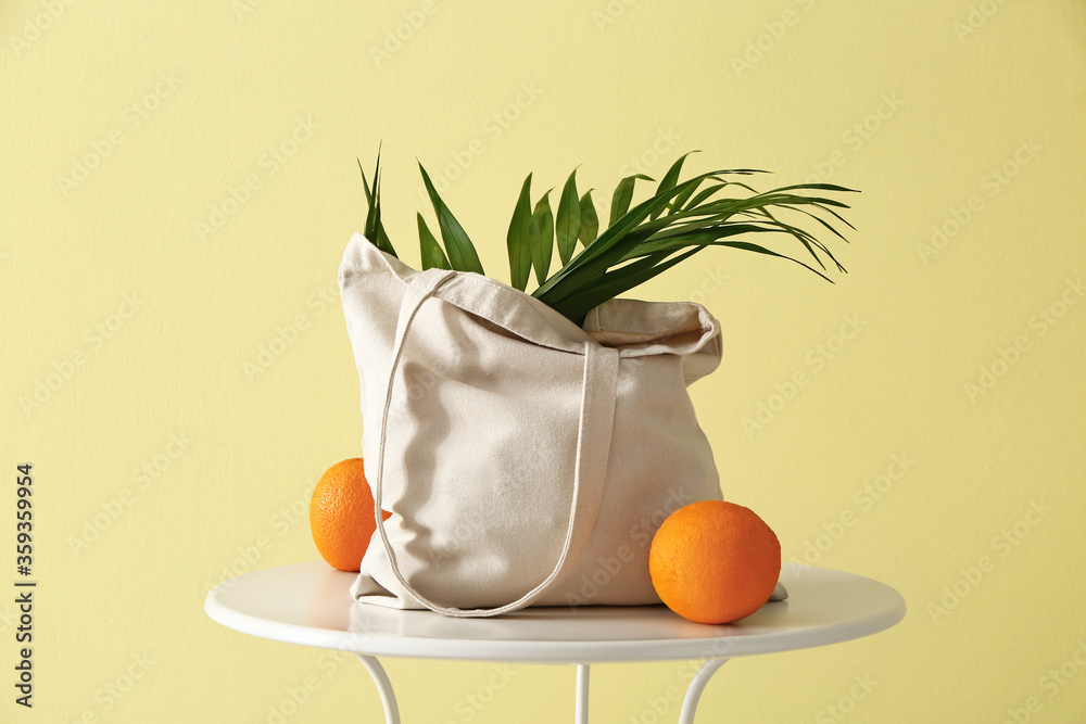 在彩色背景下，桌子上放着橙色水果的环保袋