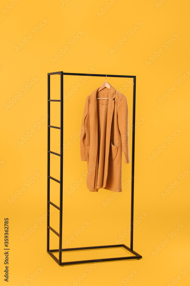 Stylish hanger with female clothes on color background
