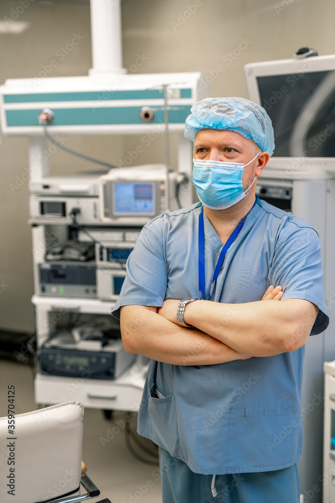 成年医生双手交叉站在手术室里。背景是特殊的现代设备。