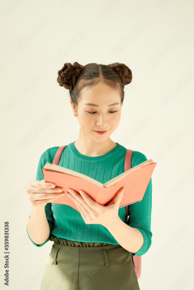 一个微笑的女青少年的肖像，背着背包，在白底上看书