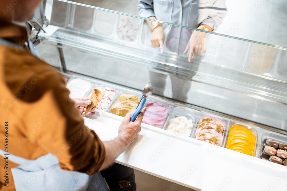 售货员用勺子从商店的冰箱里挑选冰淇淋。从托盘上俯视f