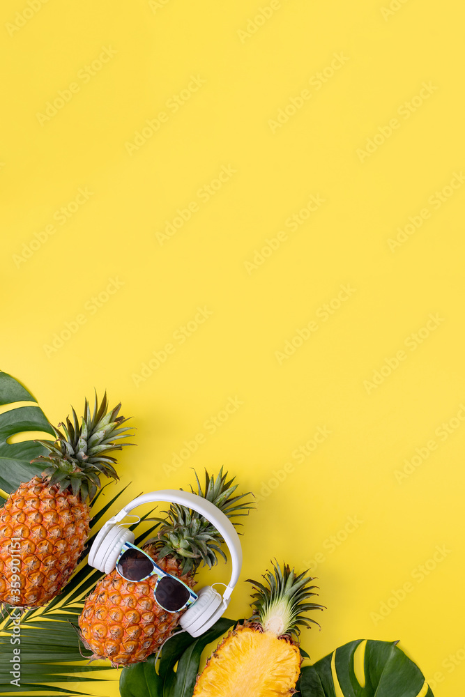 有趣的菠萝戴着白色耳机，听音乐，在黄色背景上与热带p隔离