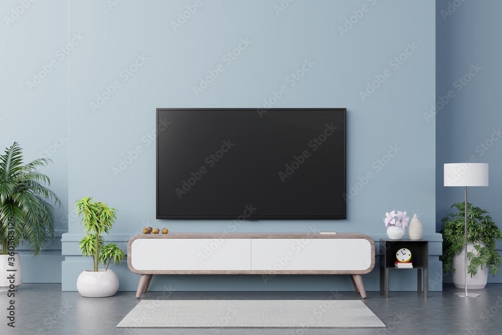 现代客厅橱柜上的电视在蓝色墙壁背景上有植物和书籍。
