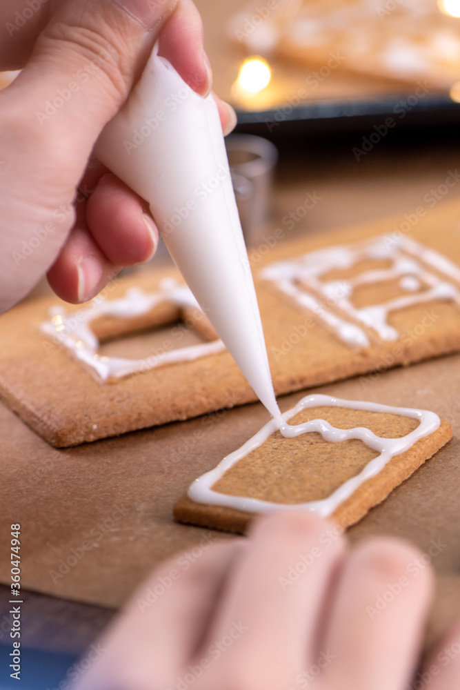 一位年轻女士正在家里用糖霜浇头装饰圣诞姜饼饼干