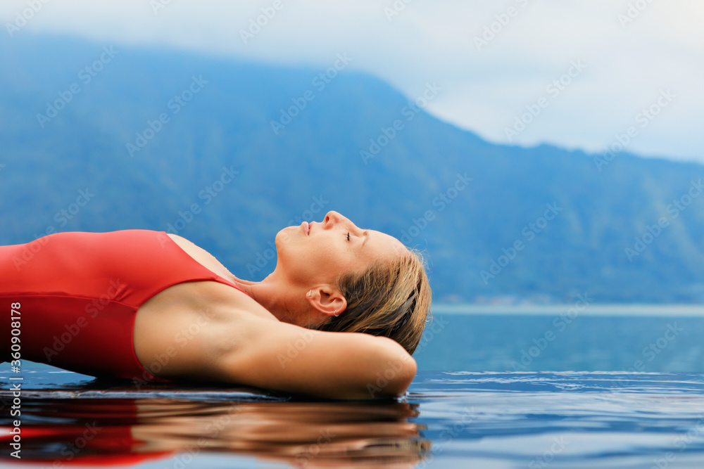 年轻女子在享有湖景的无边泳池中放松。巴图尔火山下的天然温泉水疗中心。Trave