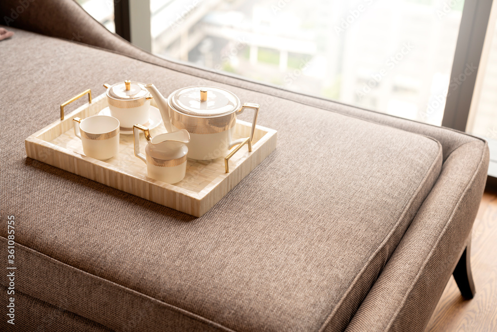 一套带小茶壶的茶或咖啡，放在木制trayon沙发上，房间内部背景i