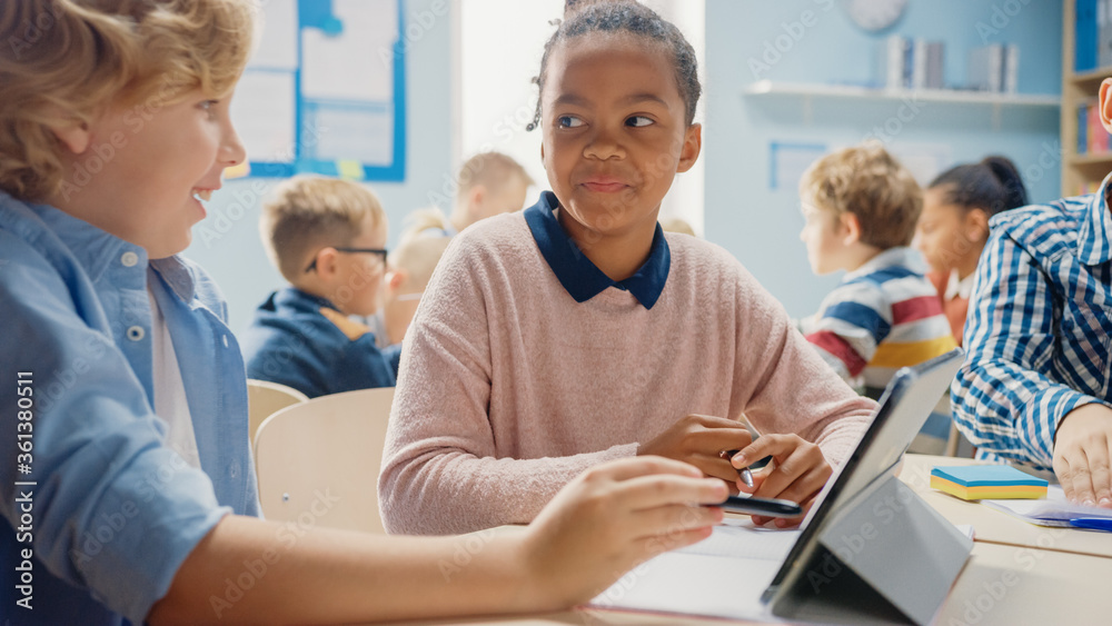 在小学：女孩和男孩一起使用平板电脑学习编程