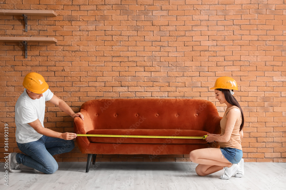 Couple with measuring tape near sofa in room