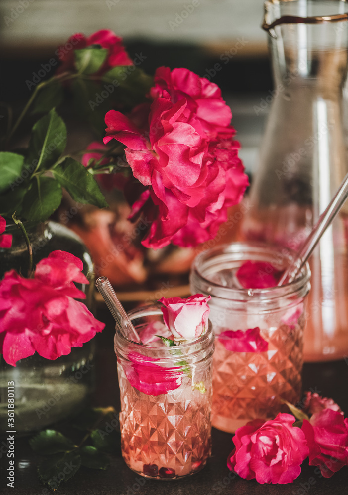 夏日清爽冷饮。玫瑰柠檬水，玻璃杯和罐子里有冰块，还有粉红色的玫瑰花瓣