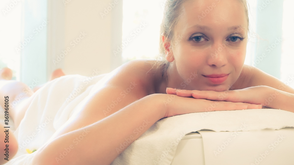 放松的年轻女子躺在水疗床上，准备在豪华水疗度假村进行面部护理和按摩。