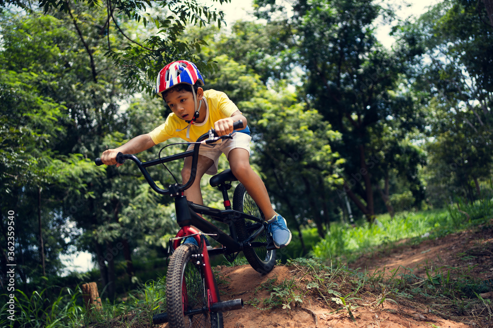 亚洲男孩正在为快乐的山地自行车训练。