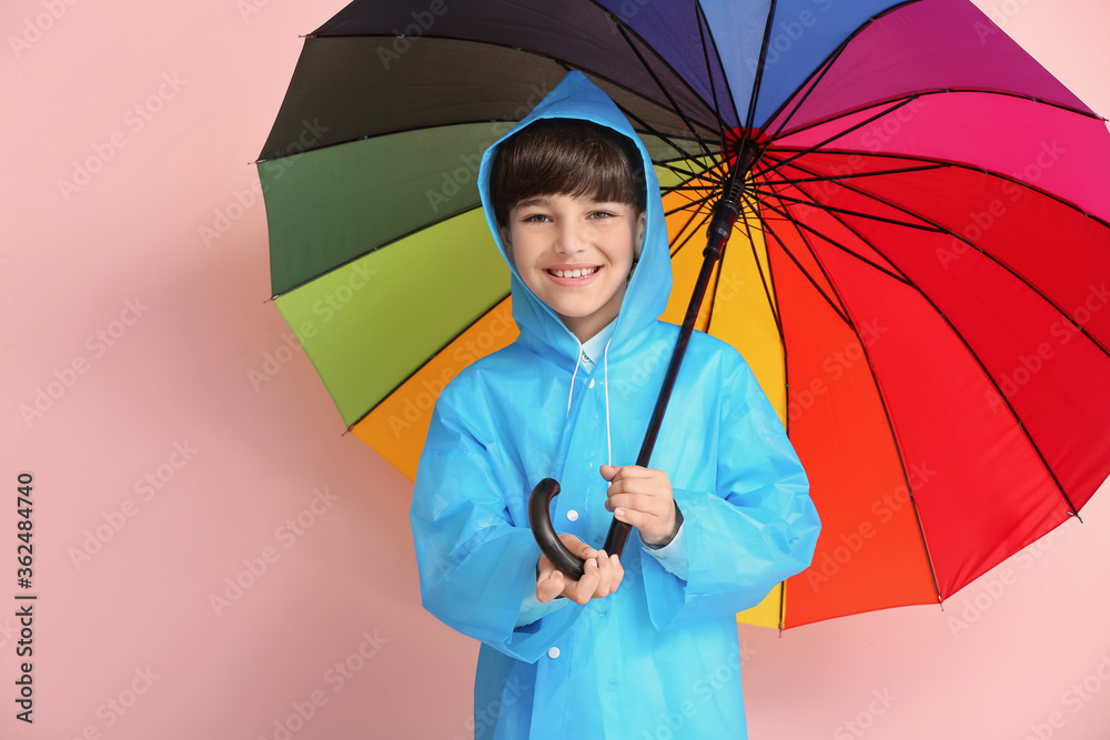可爱的小男孩穿着雨衣，背景是雨伞