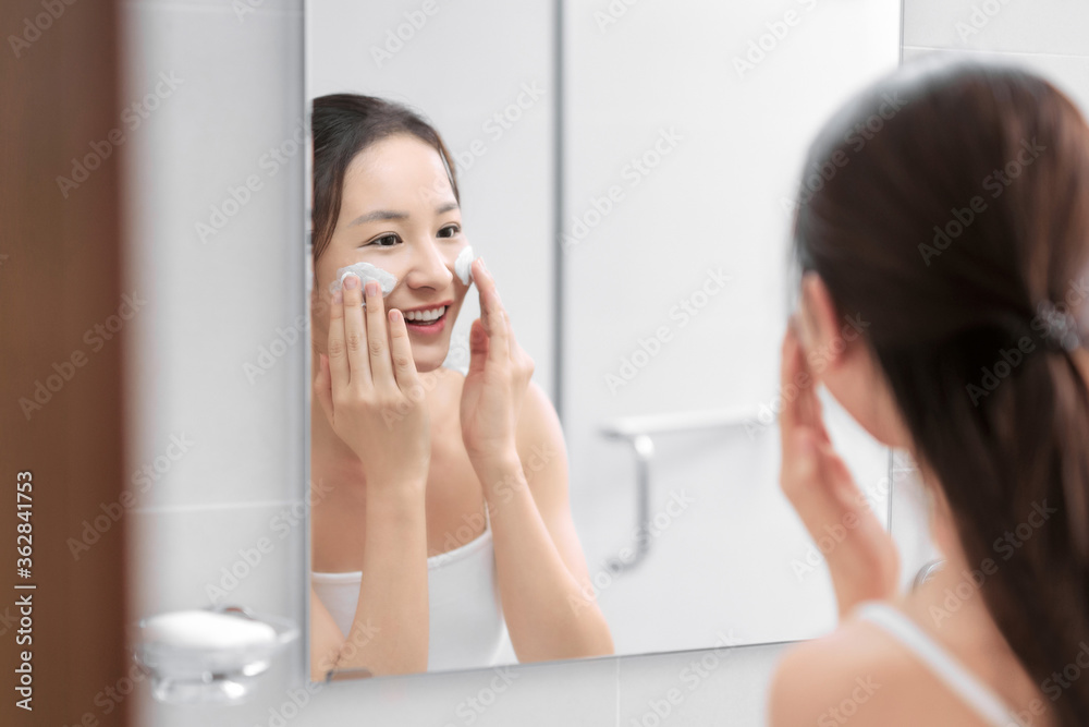 女人在浴室里用泡沫清洁皮肤。